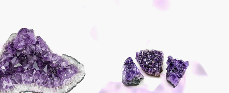 Amethyst crystal cluster showcasing various shades of purple, from light lilac to deep violet, on a white background.