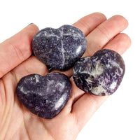 Three elegant Lepidolite Mini Hearts displayed in a hand for stunning decoration
