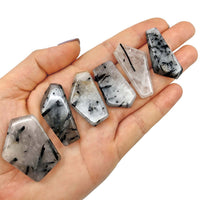 Several pieces of tourmalinated quartz polished pocket stones in a palm