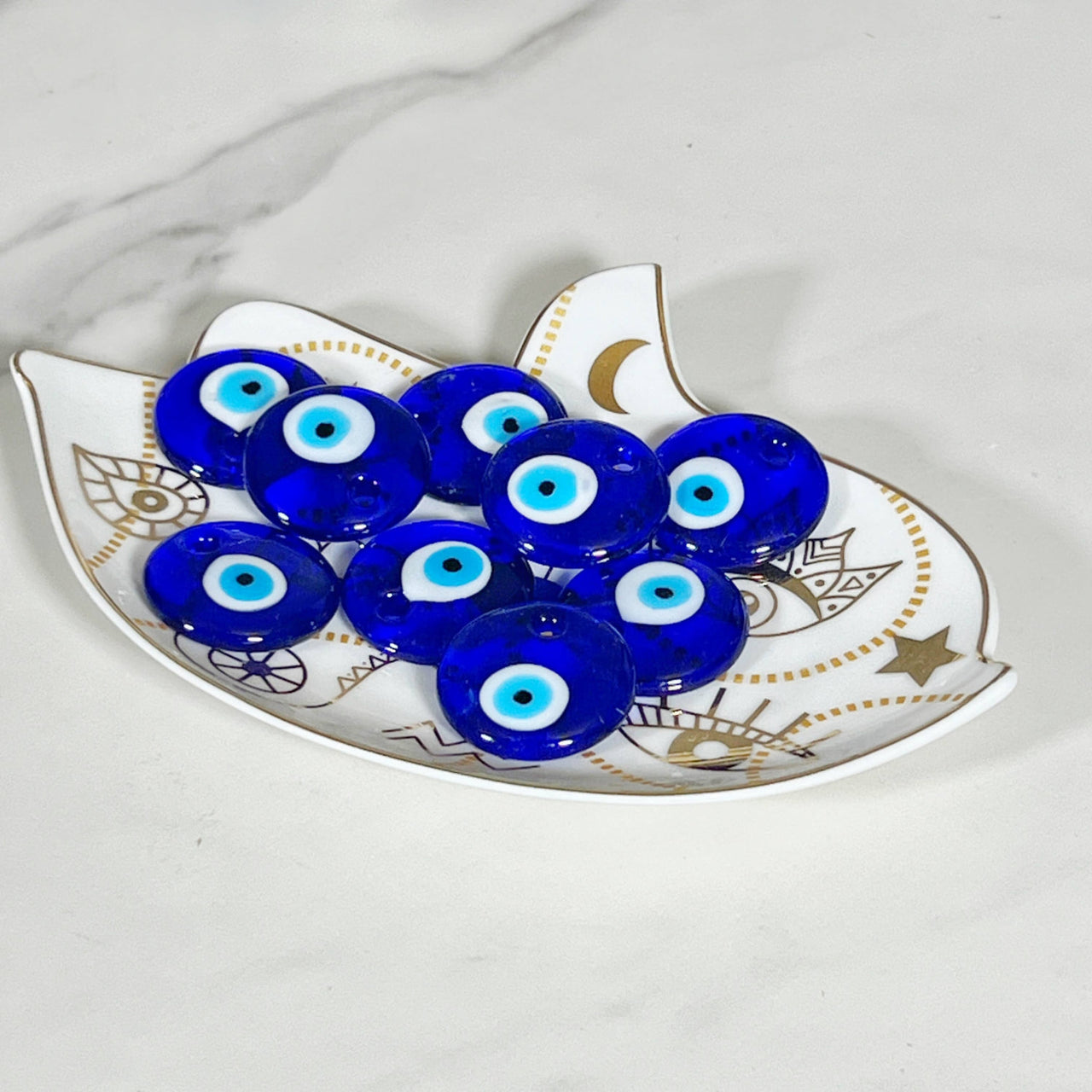 Blue evil eye glass beads on a decorative white and gold plate for protection