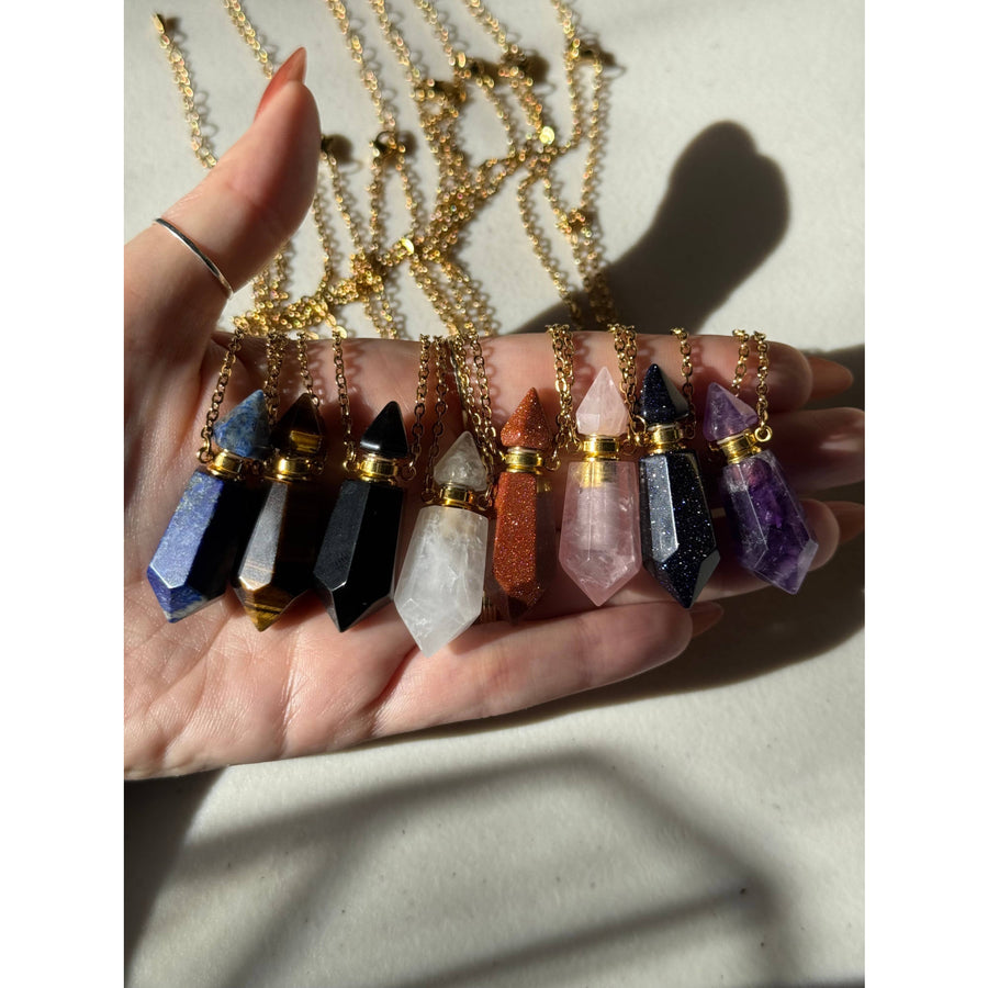Hand holding Amethyst Essential Oil Crystal Necklace pendants with gemstones