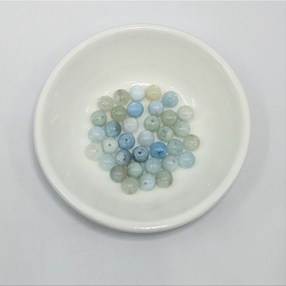 Bowl of blue and green beads from Aquamarine 6mm Round Bead 12 pack for item tier benefits