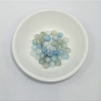 Bowl of blue and green beads from Aquamarine 6mm Round Bead 12 pack for item tier benefits