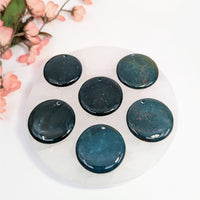 Seven polished bloodstone pendants displayed in a bloodstone 1.5-inch flat round drilled pendant