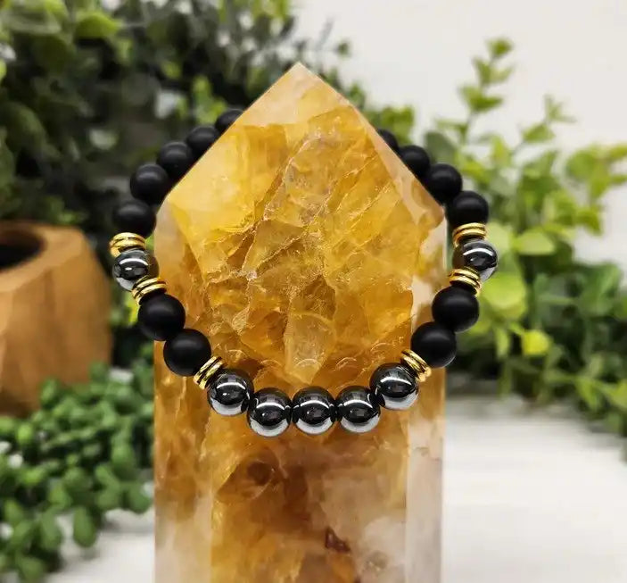 Citrine crystal point with a black and silver beaded bracelet wrapped around it.