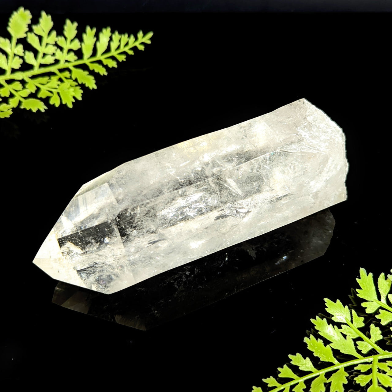 Clear quartz natural point 1 to 1.5 inch translucent crystal with pointed tip on a reflective black surface