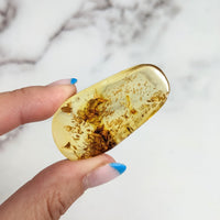Hand holding Colombian Amber 1.9’ Polished Piece #LV3151 with brown and yellow liquid inside pill