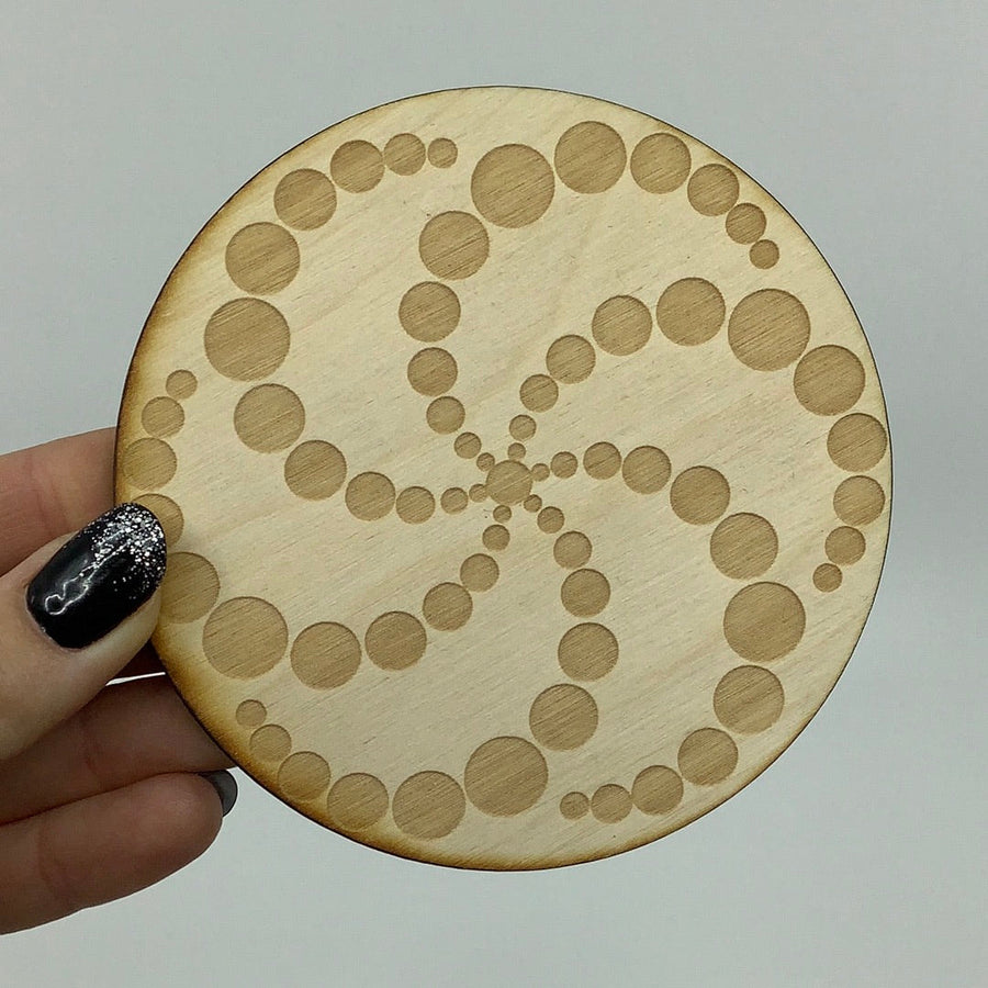A person holding an alder wood Crop Circle Crystal Grid wooden coaster with intricate circles