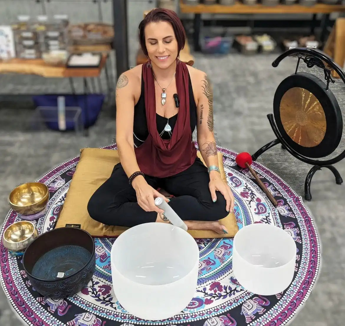 Crystal singing bowl being played on a decorative circular mandala mat.