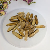Pile of translucent amber-colored African Citrine polished points for jewelry making