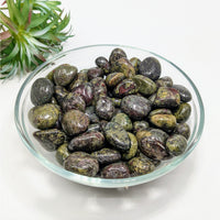 Dark polished Dragon’s Blood Jasper tumbled stones in a decorative glass bowl