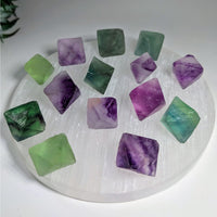 Collection of purple and green Fluorite Octahedron crystals on a white surface