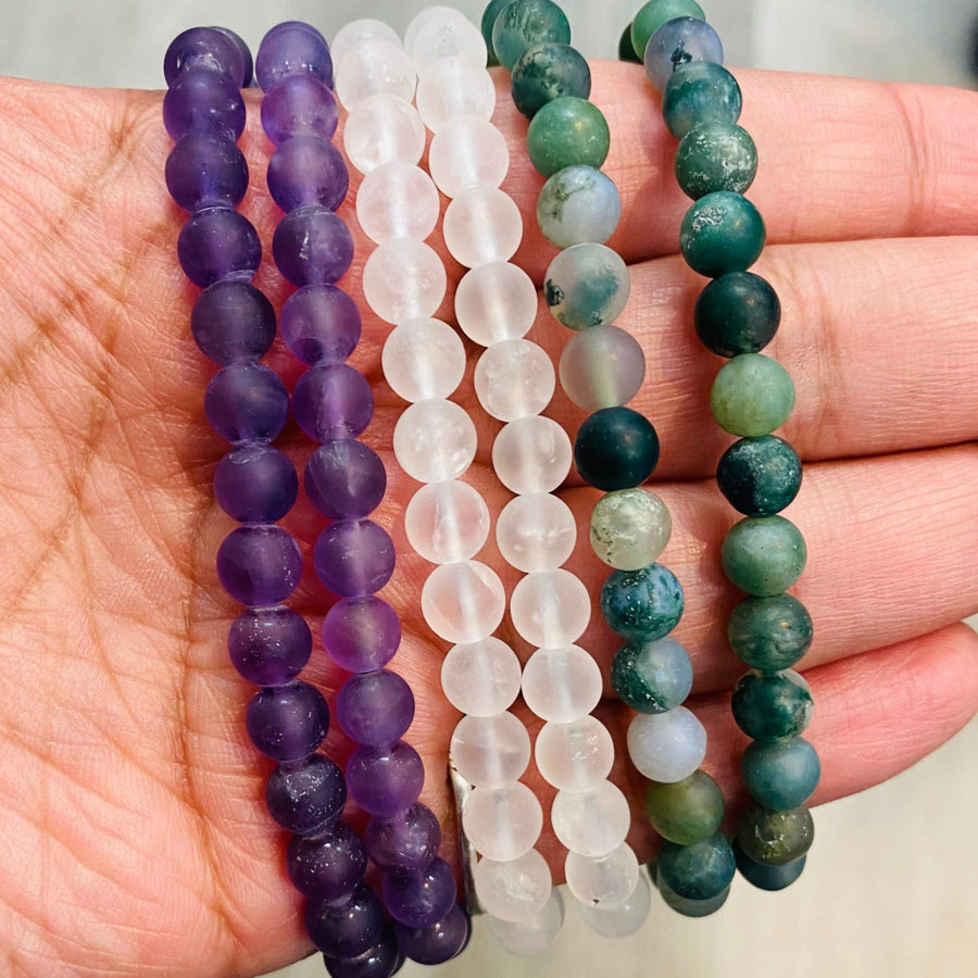 Frosted Bracelet J586 featuring purple, clear, and green-blue beads on a palm