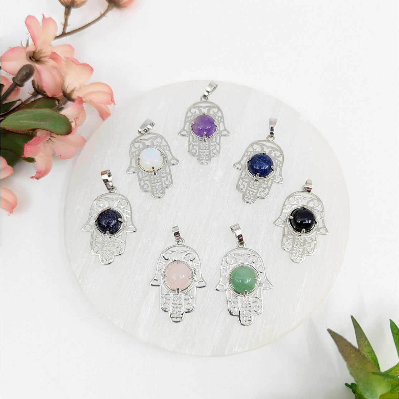 Seven silver Hamsa Fatima pendants with colorful gemstone centers displayed as product LV7912
