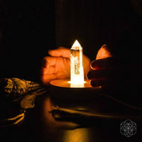 Clear quartz crystal point on flame-lit candle holder in The Healing Quartz Lamp