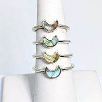 Close-up of a stack of Bliss Crystals rings with labradorite mini crescent moon and colored stones