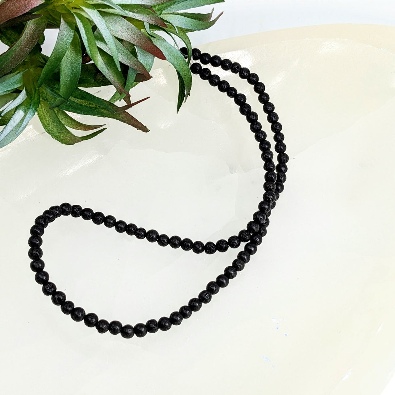 Black beaded necklace of Lava Beads 4.5mm small round strand arranged in a curve