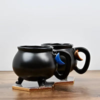 Black mug with blue handle on table, featuring Moon Crystal Tea Infuser #LV5490