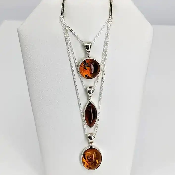 Multi-strand silver necklace with three amber-colored pendant stones arranged vertically.