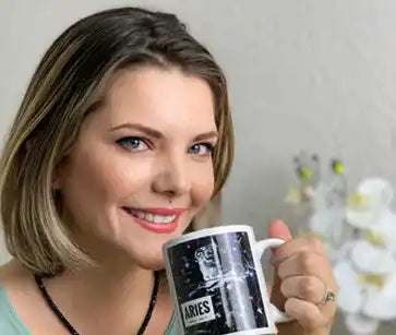 A person smiling while holding a black and white coffee mug.
