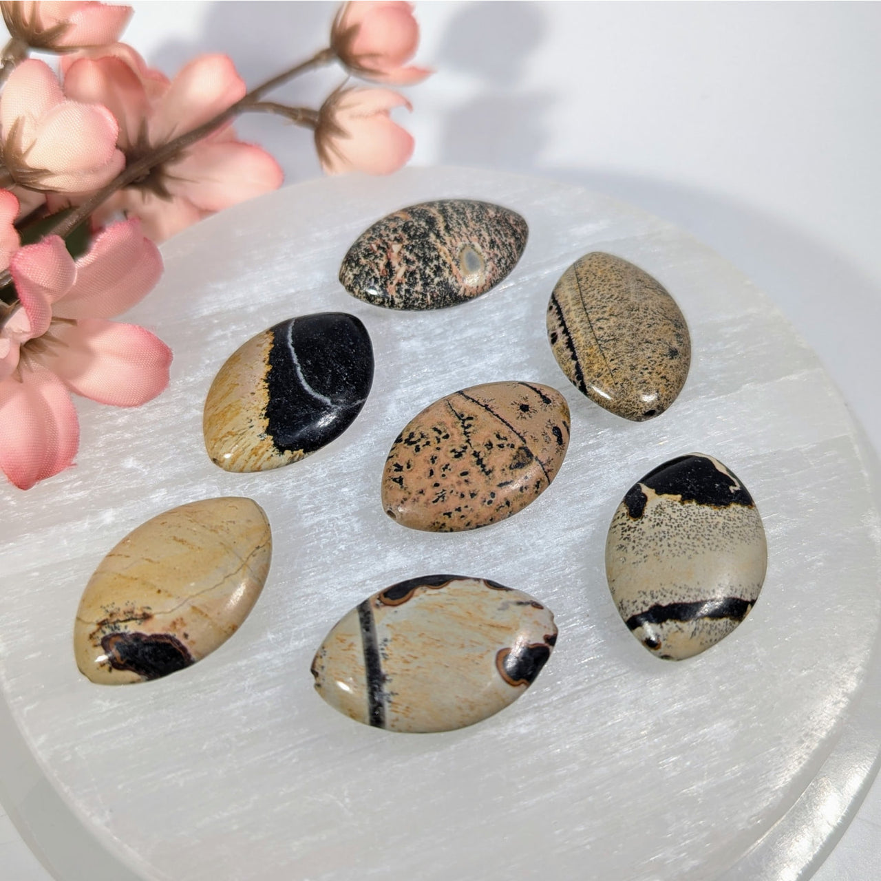 Seven polished Picture Jasper 30mm oval beads on white crystal plate