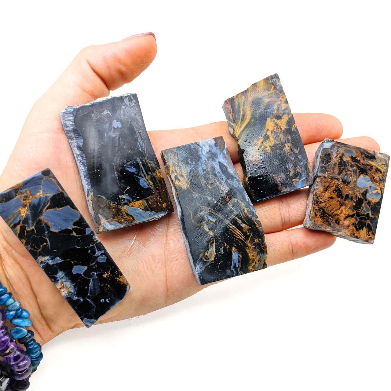 Five dark Pietersite unpolished slab pieces showcasing unique blue and orange-brown patterns