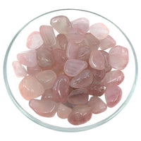 Polished Pink Girasol Quartz crystals displayed in a glass dish for tumbled stones