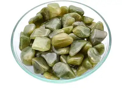 Polished green serpentine stones in a glass bowl.