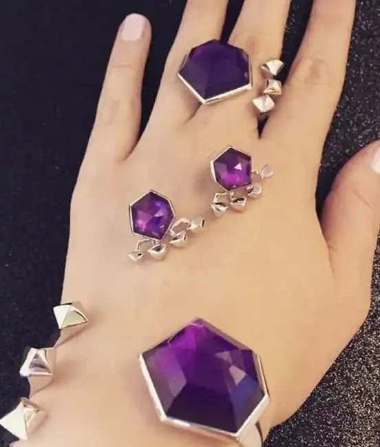 Purple hexagonal gemstone jewelry set with silver accents displayed on a hand.