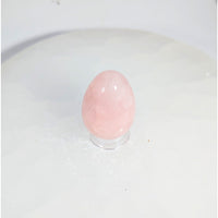 Smooth translucent pink rose quartz yoni egg with hole on acrylic stand