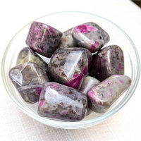 Polished Ruby Feldspar Tumbled stones in a bowl showcasing vibrant ruby zoisite for referral history