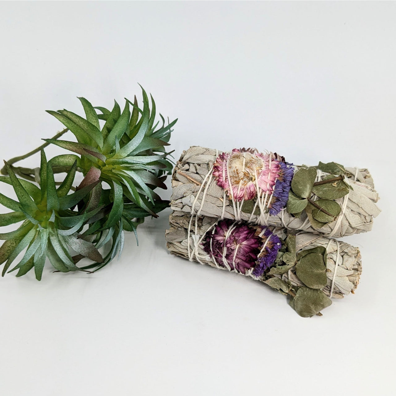 Two sage bundles with dried flowers for cleansing rituals in Sage & Herb Cleansing Smudge Stick Bundles #K120