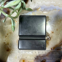Dark gray Shungite cellphone holder with built-in ruler on stone stand