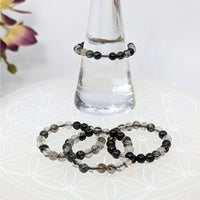 Black and clear beaded bracelets displayed on a tourmalinated quartz stretch ring