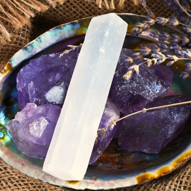 White selenite crystal wand alongside purple amethyst clusters.